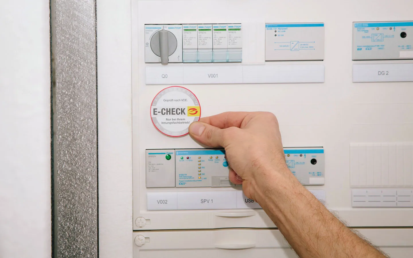 E-CHECK - Mitarbeiter klebt in der Verteilung die E-CHECK Plakette an &middot; Elektro Hammes GmbH
