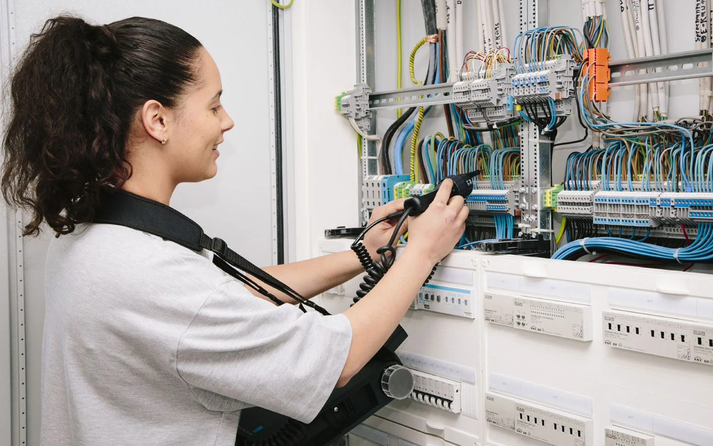 E-CHECK - Mitarbeiterin prüft im Schaltschrank mit einem Meßgerät &middot; Elektro Hammes GmbH